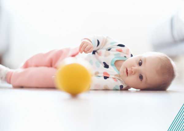 Baby rolling over to reach ball