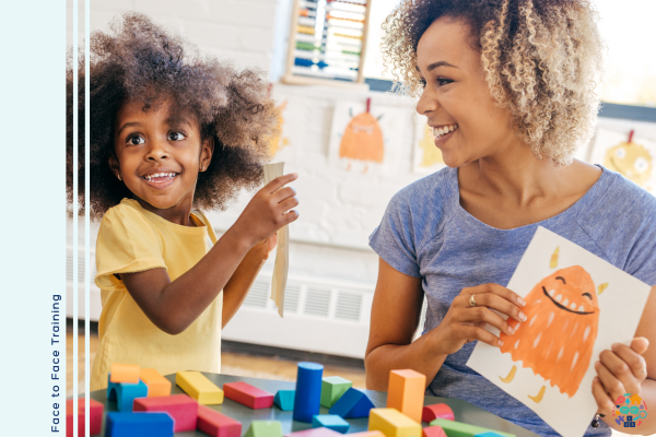 Child shows off her painting to and adult who is also holding up her painting of a yellow monster.