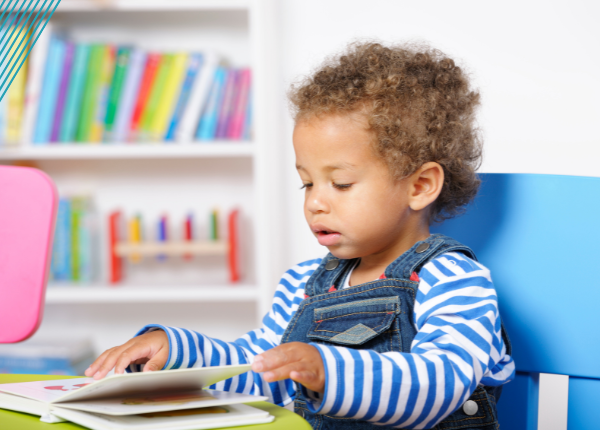 Child wearing dungarees reading book