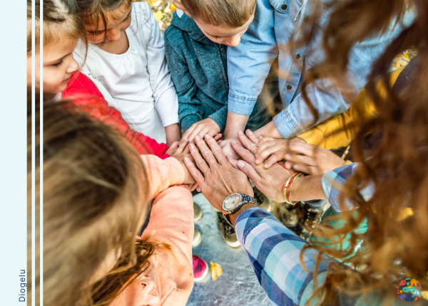 Children and adults stood in a circle stacking hands