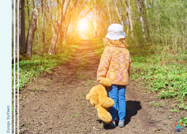 Child holding a teddy walk along a path lined with trees