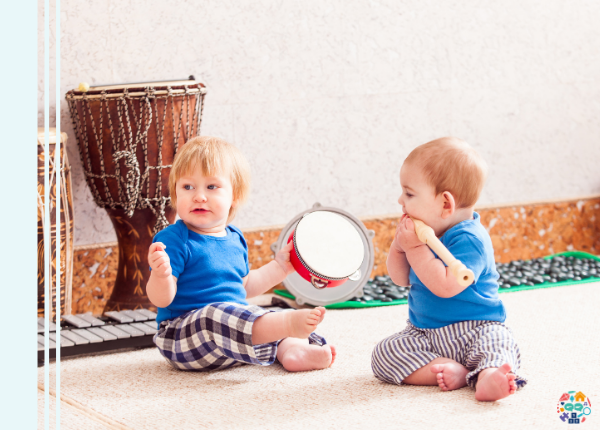 Two toddlers are playing with instruments, one is holding a tamborine while the other has a recorder