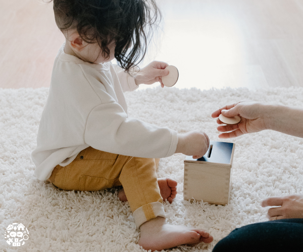 Child putting a wooden coin into a wooden money box