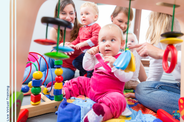 Baby wearing bright pink dungarees points to ear