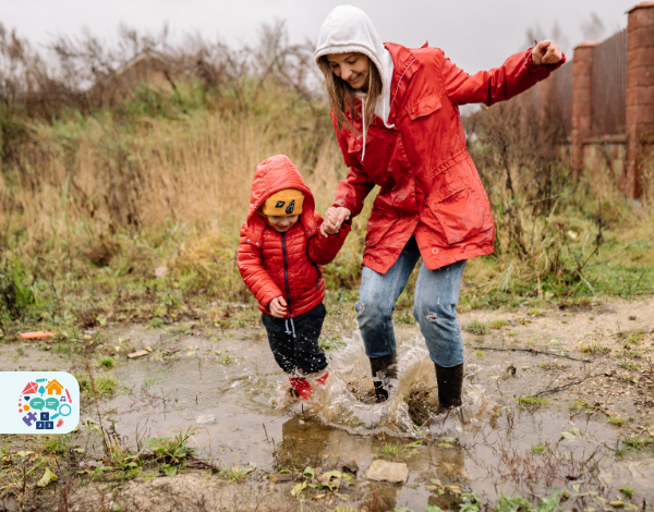 Image of an adult and child wearing red coats jumping in puddles