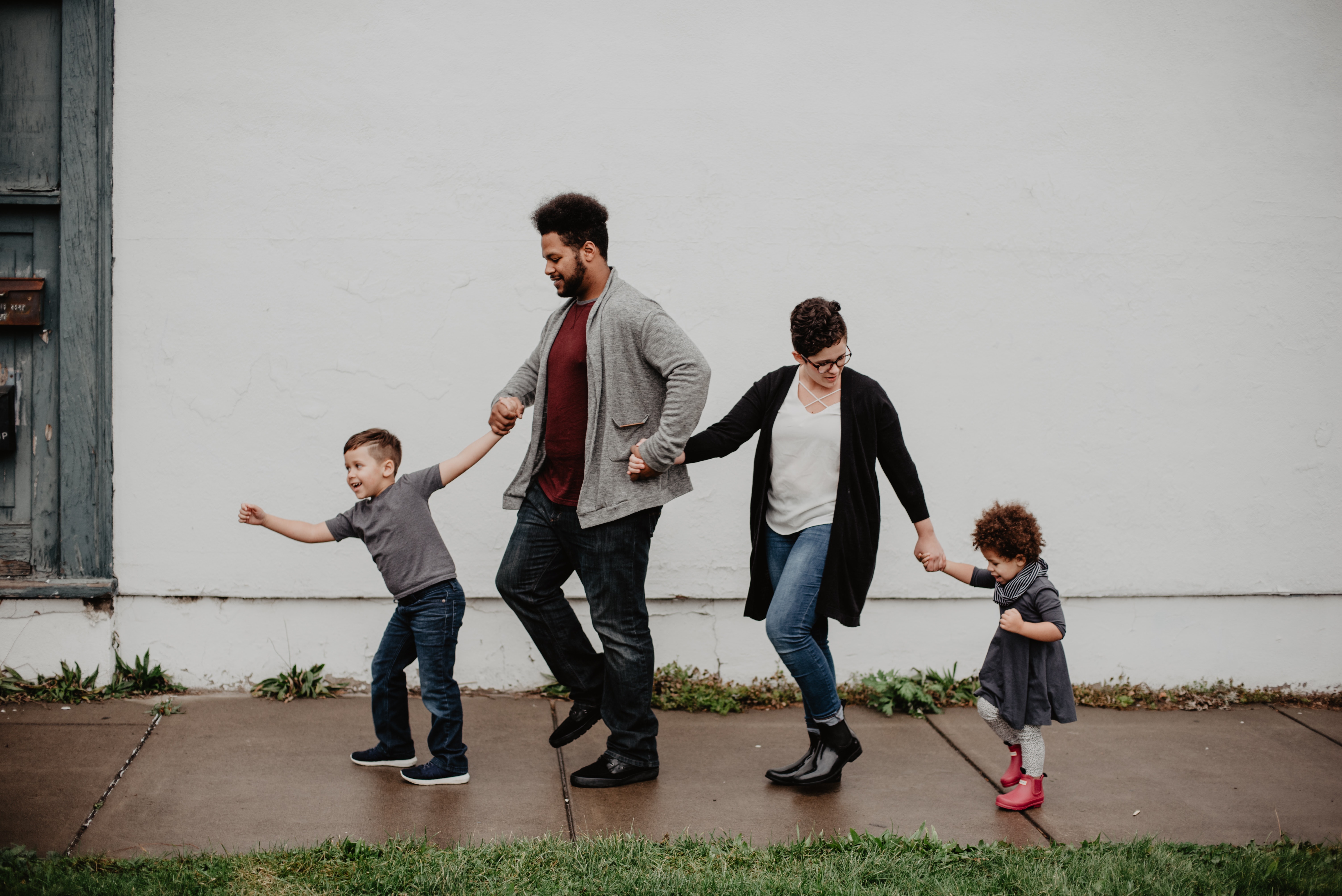 parents and young children holding hands walking down the street