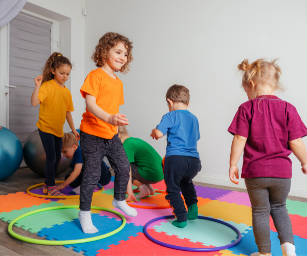 Children wearing colourful tops play with hoops