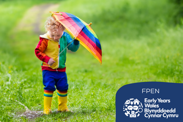 Child in brightly coloued clothes and umbrella steps in a puddle