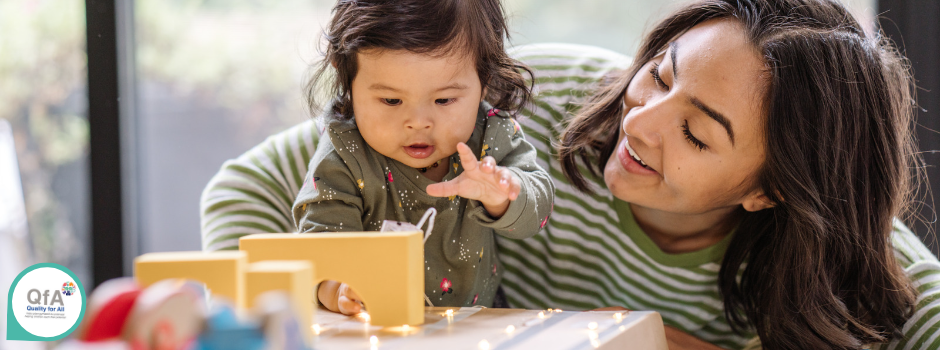 What are the benefits? Adult smiling while child reaches for block