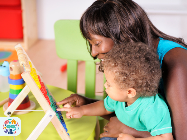 Adult wearing a blue tank top holding child wearing a blue top adds up using an abacus