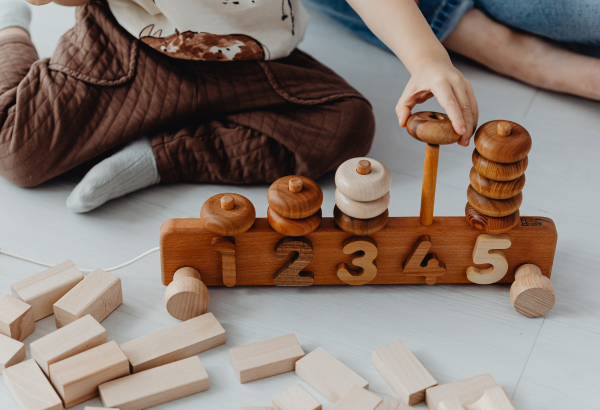 Child playing a wooden ring on a row of blocks