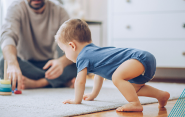 Child in blue romper crawling towards item