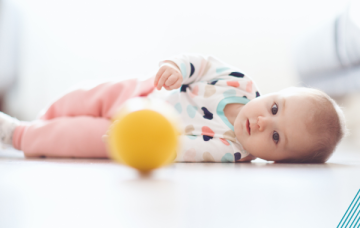 Baby rolling over to reach ball