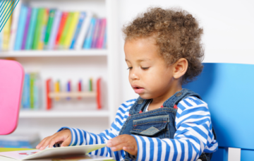 Child wearing dungarees reading book