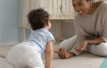 Adult encouraging crawling baby forward