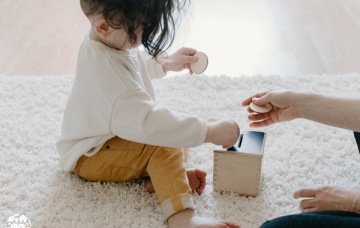 Child putting a wooden coin into a wooden money box
