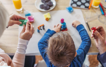 Child sat in between two adults playing with playdough