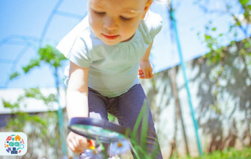 Image of a child examining flowers with a magnifying glass