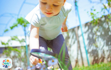 Image of a child examining flowers with a magnifying glass