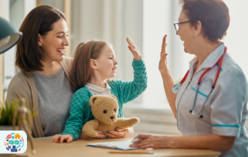 Image of child sitting on adult's lap high fiving a medical professional