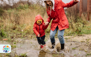 Image of an adult and child wearing red coats jumping in puddles