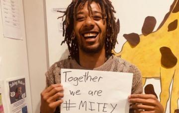 Smiling gentleman holdonhg a Together we are #Mitey card