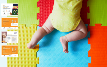 Baby in a yellow and white polka dot babygrow doing tummy time on colourful mats