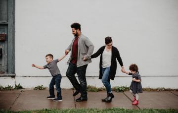 parents and young children holding hands walking down the street