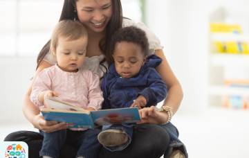 Picture of an adult reading a book to two babies who are sat on her lap