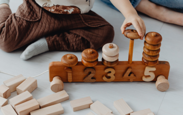 Child playing a wooden ring on a row of blocks