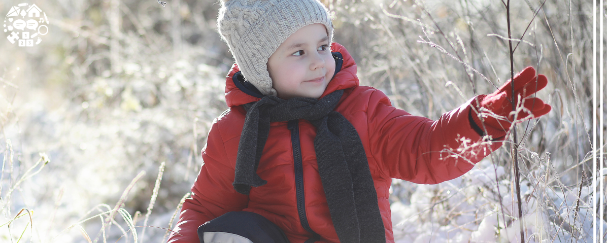 Child dressed in winter clothing explores a snowy landscape