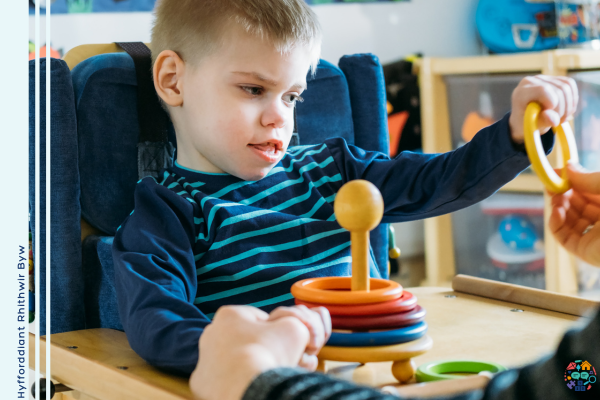Child wearing a navy and blue striped shirt is playing with a set of wooden rings