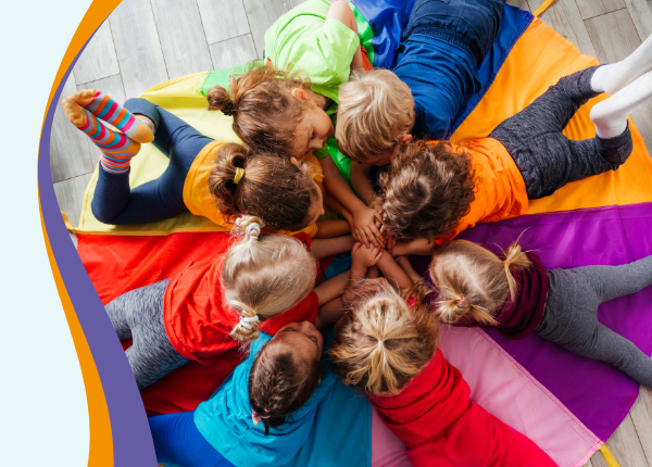 Children laying on a colourful parachute stacking hands